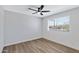 Neutral bedroom with wood-look floors, white walls, a ceiling fan, and a large window at 4347 E Catalina Cir, Mesa, AZ 85206