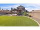 Wide backyard with manicured lawn, mature palm trees, and a home with an elevated wooden balcony at 4547 E Buist Ave, Phoenix, AZ 85044