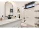 Bright bathroom features a black framed arched mirror, neutral countertops, and shower-tub combo at 527 N Criss St, Chandler, AZ 85226