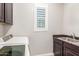 Laundry room featuring a sink, dark cabinets, and modern washing machine under bright window at 6251 E Bramble Berry Ln, Cave Creek, AZ 85331