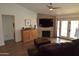 Cozy living room featuring a stone fireplace, modern TV, wood flooring, and a comfortable leather sofa at 6352 W Campo Bello Dr, Glendale, AZ 85308
