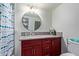 Bathroom showcasing a cherry vanity, circular mirror, shower with curtain, and toilet at 7111 N 63Rd Dr, Glendale, AZ 85301