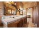 Bathroom featuring double sinks, decorative mirrors, and rustic-inspired cabinetry at 9030 E Trail Dr, Carefree, AZ 85377