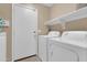 Bright laundry room featuring a white washer and dryer, storage shelves, and a convenient access door at 925 W San Marcos Dr, Chandler, AZ 85225