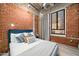 Charming bedroom featuring exposed brick walls, a cozy bed with stylish pillows, and a window with natural light at 114 W Adams St # 202, Phoenix, AZ 85003