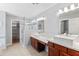 Bathroom featuring dual sinks, wood cabinets, tile floors, and a glass shower at 1201 E Campbell Ave, Gilbert, AZ 85234
