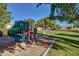 A playground with a slide and various climbing structures, surrounded by green grass and mature trees at 1201 E Campbell Ave, Gilbert, AZ 85234