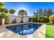 Backyard pool with palm tree, privacy wall, lush landscaping, and clear blue sky at 1201 E Campbell Ave, Gilbert, AZ 85234