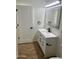 Bathroom with a white vanity, black hardware, wood-look floors, and an illuminated mirror for a modern aesthetic at 1309 E Julie Dr, Tempe, AZ 85283