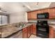 Functional kitchen with stainless steel sink, wood cabinets, black appliances, and a countertop overlooking the living area at 1331 W Baseline Rd # 167, Mesa, AZ 85202