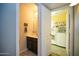 Charming half bathroom featuring a dark vanity, decorative mirror, and a view into the laundry room at 1750 E Erie St, Gilbert, AZ 85295