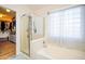 Well-lit bathroom with glass enclosed shower and a soaking tub with a window and stylish curtains at 1750 E Erie St, Gilbert, AZ 85295