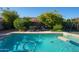 Outdoor in-ground pool is surrounded by landscaping, furniture, and trees at 1750 E Erie St, Gilbert, AZ 85295