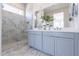 Sleek primary bathroom with marble tile, dual sinks, and glass-enclosed shower at 18047 W Long Lake Rd, Goodyear, AZ 85338