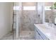 Modern bathroom with a glass-enclosed shower featuring stylish marble tile and a sleek, gray vanity with white countertop at 18047 W Long Lake Rd, Goodyear, AZ 85338