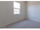 This is a bedroom with gray carpeting and a window that allows natural light to come in at 18047 W Long Lake Rd, Goodyear, AZ 85338