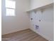 Clean laundry room with floating shelves, light wood flooring, and a window for ventilation and natural light at 18047 W Long Lake Rd, Goodyear, AZ 85338
