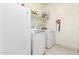 Functional laundry room with white appliances, open shelving, and tile flooring at 18241 W Foothill Dr, Surprise, AZ 85387