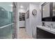 Elegant bathroom featuring a modern shower with glass door, dark vanity and access to the walk-in closet at 20769 N 106Th Ln, Peoria, AZ 85382