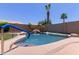 A private backyard pool area with a rock waterfall feature, palm trees, and a grassy area at 20769 N 106Th Ln, Peoria, AZ 85382