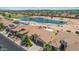 Aerial view of a neighborhood with a lake, golf course, tile roofs, palm trees, and desert landscaping at 2163 N 164Th Dr, Goodyear, AZ 85395