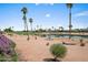 Scenic view of a golf course community with palm trees, a pond, and lush landscaping under a bright sky at 2163 N 164Th Dr, Goodyear, AZ 85395