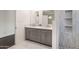 Bright bathroom featuring double vanity, modern mirrors, marble floors, and stylish tiled shower with built-in shelves at 3102 E Mariposa St, Phoenix, AZ 85016