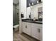 Stylish bathroom with double vanity sink, gray tiled shower, white cabinets, black hardware and light tile flooring at 3419 W Sunstone Dr, San Tan Valley, AZ 85144