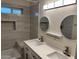 Modern bathroom featuring a double vanity with round mirrors and gray, subway-style tile in shower at 344 E Aepli Dr, Tempe, AZ 85282