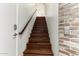 Interior staircase featuring hardwood steps, white walls, and brick accent wall at 3633 N 3Rd Ave # 2031, Phoenix, AZ 85013