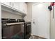 Modern laundry room with a front-load washer and dryer, upper cabinets, and a door leading outside at 4137 E Stanford Ave, Gilbert, AZ 85234