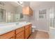 Bathroom featuring wood cabinets, double sinks and a walk-in shower at 42551 W Anne Ln, Maricopa, AZ 85138