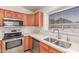 Well-lit kitchen featuring stainless steel appliances, light countertops, and wood cabinets at 42551 W Anne Ln, Maricopa, AZ 85138