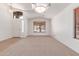 Bright, open living room featuring neutral carpet, and abundant natural light from the front door and dual windows at 42551 W Anne Ln, Maricopa, AZ 85138