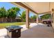 Covered backyard patio with an outdoor kitchen, seating area, and well-maintained lawn at 44517 W Copper Trl, Maricopa, AZ 85139