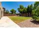 Beautifully landscaped backyard featuring lush green grass, mature trees, and a seating area at 44517 W Copper Trl, Maricopa, AZ 85139