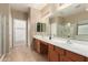 Bright bathroom featuring double sinks, modern fixtures, a large mirror, and a walk-in shower at 44517 W Copper Trl, Maricopa, AZ 85139