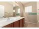 Neutral-toned bathroom featuring a large mirror and spacious vanity with dark wood cabinets at 44517 W Copper Trl, Maricopa, AZ 85139
