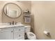 A powder room featuring a stylish round mirror, a vessel sink, and a modern toilet at 44517 W Copper Trl, Maricopa, AZ 85139