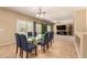 Elegant dining room with a glass-top table, comfortable chairs, and sliding glass doors to the backyard at 44517 W Copper Trl, Maricopa, AZ 85139