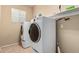 Bright laundry room with front-load washer and dryer and upper storage shelf at 44517 W Copper Trl, Maricopa, AZ 85139