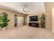 Cozy living room with carpet, a ceiling fan, large windows, and a stylish entertainment center at 44517 W Copper Trl, Maricopa, AZ 85139
