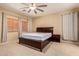 A spacious main bedroom with a dark wood bed frame, a ceiling fan, and neutral walls at 44517 W Copper Trl, Maricopa, AZ 85139