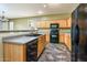 Open-concept kitchen with wood cabinets, black appliances, and views into the dining area at 45391 W Portabello Rd, Maricopa, AZ 85139