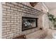 Close-up of a brick fireplace with glass doors and decorative fireplace tools at 5237 N 106Th Ave, Glendale, AZ 85307
