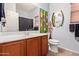 Well-lit bathroom with wood vanity, neutral-colored walls, decorative artwork and mirror, and tile flooring at 5314 W Bowker St, Laveen, AZ 85339