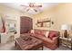 Comfortable living room featuring a leather sectional, ottoman, shuttered windows and ceiling fan at 5314 W Bowker St, Laveen, AZ 85339