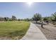 Scenic walking path through a park featuring green grass, mature trees, and clear blue sky at 6922 S Black Hills Way, Chandler, AZ 85249