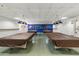 A billiards room features multiple tables covered with protective tarps, with lighting and decor in place at 701 S Dobson Rd # 447, Mesa, AZ 85202