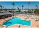 Aerial view of a community pool with lounge chairs and palm trees in a sunny neighborhood at 701 S Dobson Rd # 447, Mesa, AZ 85202